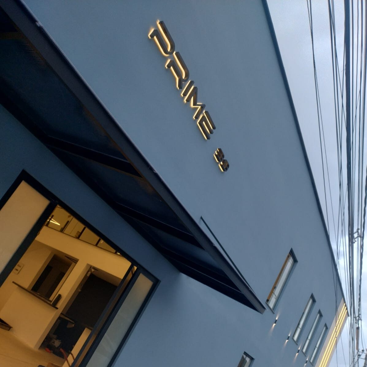 Fachada de um grande salão de festa com iluminação quente e janelas amplas. aluguel de salão de festas infantil, casamento, aniversário em campo grande, guaratiba, magarça, zona oeste do rio de janeiro.